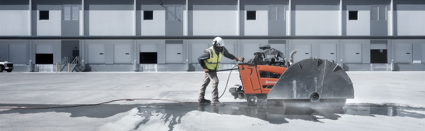 Husqvarna walk-behind flat saw cutting a large concrete slab, wet cut with slurry